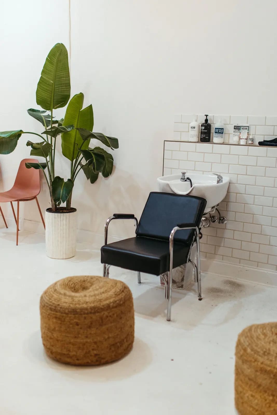 Interior luminoso de un salón con silla, lavacabezas y plantas