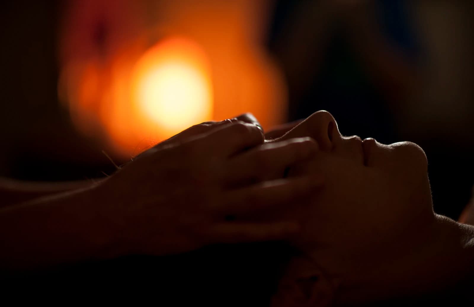Manos de una terapeuta durante un masaje facial en un spa con luz cálida